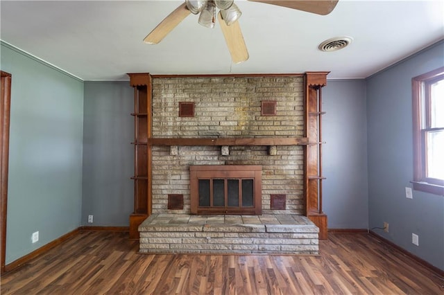 1610 N 3rd St, Neodesha, KS 66757 - unfurnished living room featuring wood finished floors, a ceiling fan, a brick fireplace, and ornamental molding