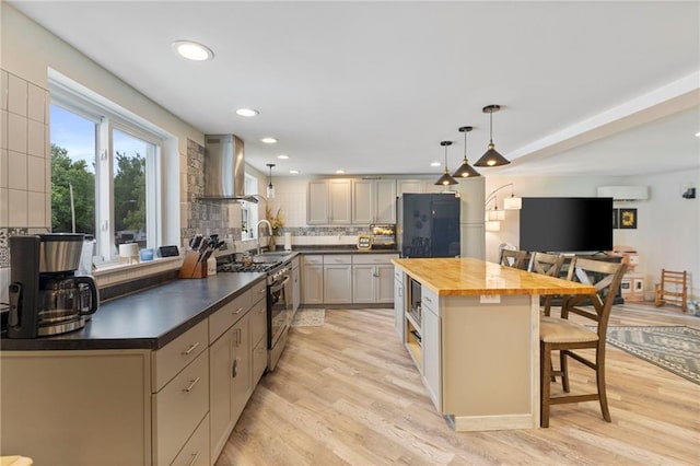 4901 E 215th St, Belton, MO 64012 - kitchen featuring wall chimney range hood, appliances with stainless steel finishes, a kitchen breakfast bar, wooden counters, and tasteful backsplash
