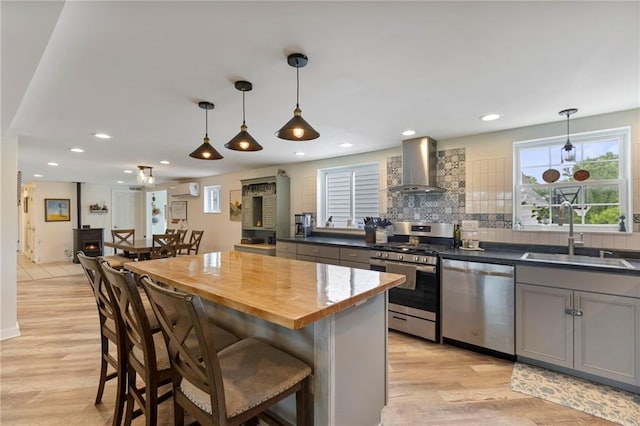 4901 E 215th St, Belton, MO 64012 - kitchen with stainless steel appliances, wall chimney exhaust hood, light wood-type flooring, a kitchen breakfast bar, and recessed lighting