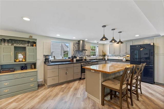4901 E 215th St, Belton, MO 64012 - kitchen featuring stainless steel gas stove, freestanding refrigerator, wall chimney range hood, decorative backsplash, and recessed lighting