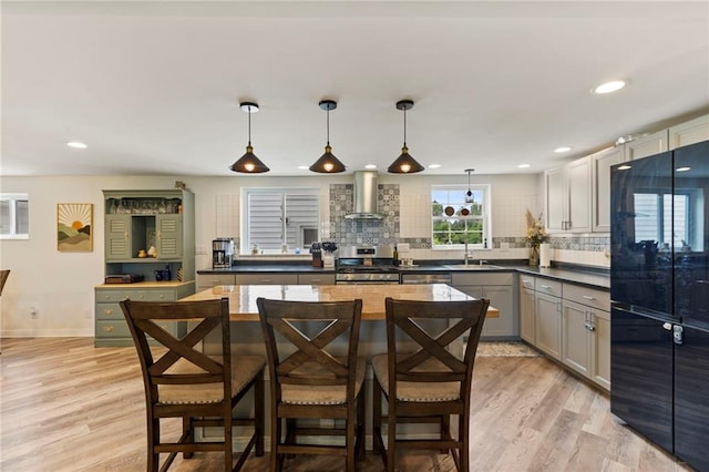 4901 E 215th St, Belton, MO 64012 - kitchen with stainless steel stove, wall chimney exhaust hood, decorative backsplash, light wood-style flooring, and recessed lighting