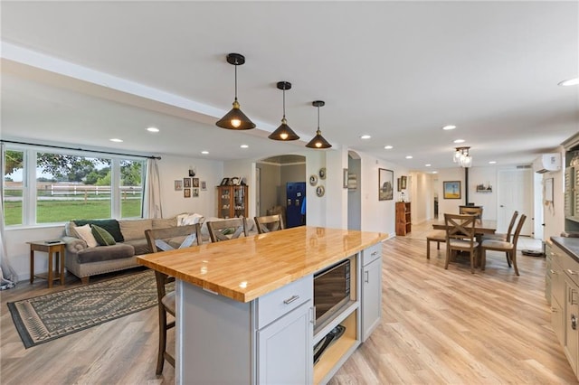 4901 E 215th St, Belton, MO 64012 - kitchen featuring a kitchen bar, open floor plan, stainless steel microwave, butcher block countertops, and hanging light fixtures