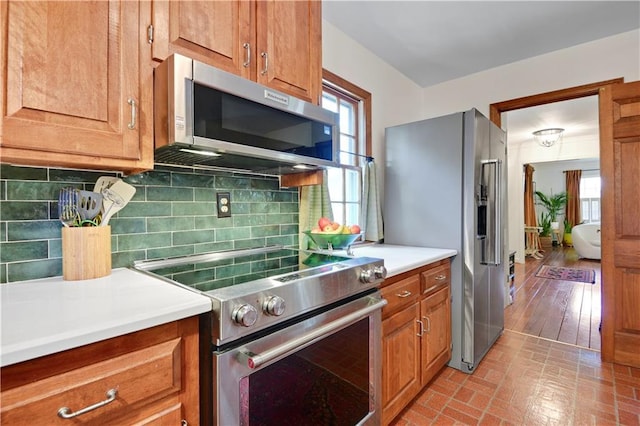4912 W 69th St, Prairie Village, KS 66208 - kitchen with stainless steel appliances, light countertops, tasteful backsplash, brown cabinets, and brick patterned flooring