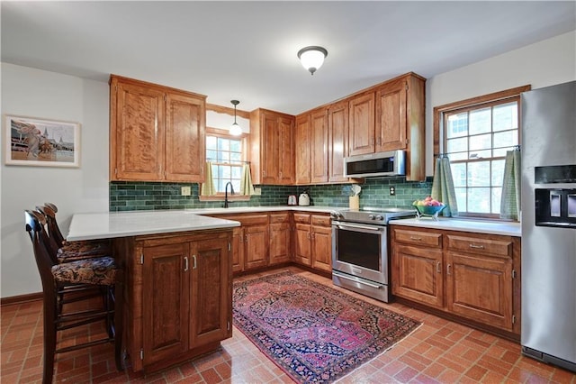 4912 W 69th St, Prairie Village, KS 66208 - kitchen with stainless steel appliances, a peninsula, light countertops, backsplash, and brown cabinetry