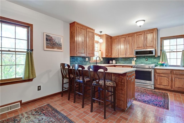 4912 W 69th St, Prairie Village, KS 66208 - kitchen with stainless steel appliances, plenty of natural light, tasteful backsplash, and a kitchen bar