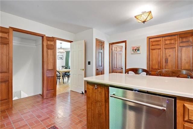 4912 W 69th St, Prairie Village, KS 66208 - kitchen featuring stainless steel dishwasher, brick patterned flooring, light countertops, and brown cabinetry