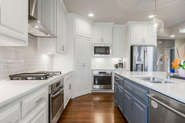 15801 Canterbury St, Overland Park, KS 66224 - kitchen featuring appliances with stainless steel finishes, wall chimney range hood, blue cabinetry, white cabinets, and light countertops