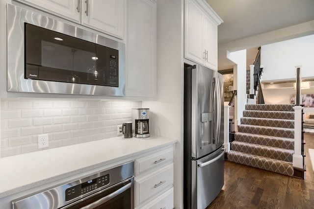 15801 Canterbury St, Overland Park, KS 66224 - kitchen with appliances with stainless steel finishes, dark wood-type flooring, white cabinetry, decorative backsplash, and light stone countertops