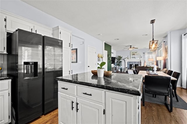 22116 W 51st St, Shawnee, KS 66226 - kitchen featuring black refrigerator with ice dispenser, wood finished floors, a fireplace, white cabinetry, and ceiling fan