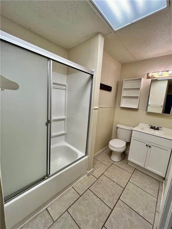 551 S Brookside Ave, Independence, MO 64053 - full bath with vanity, enclosed tub / shower combo, tile patterned flooring, and a textured ceiling