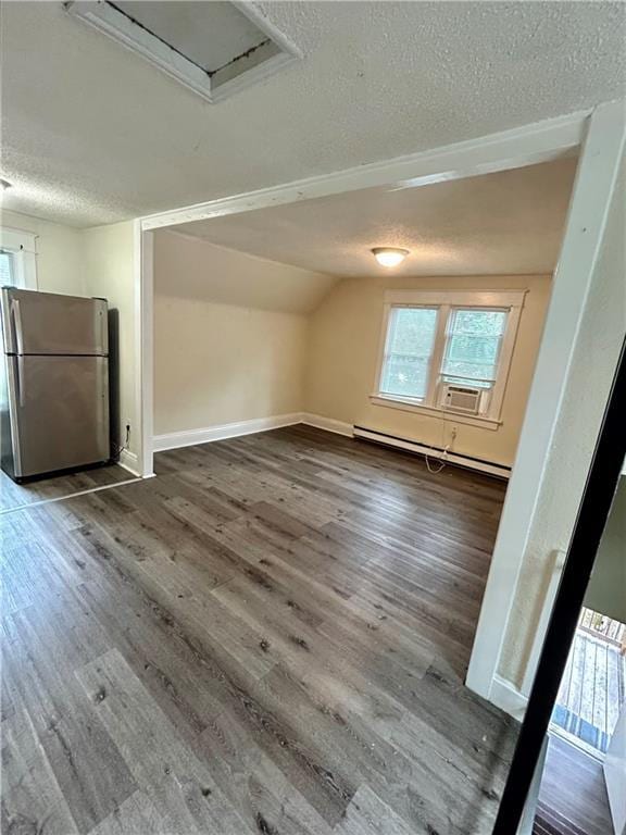 551 S Brookside Ave, Independence, MO 64053 - additional living space with a baseboard heating unit, a textured ceiling, healthy amount of natural light, dark wood-type flooring, and vaulted ceiling