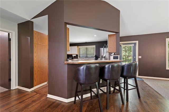 4813 NW Northwood Rd, Riverside, MO 64150 - kitchen featuring stainless steel fridge, dark wood finished floors, a kitchen breakfast bar, vaulted ceiling, and plenty of natural light