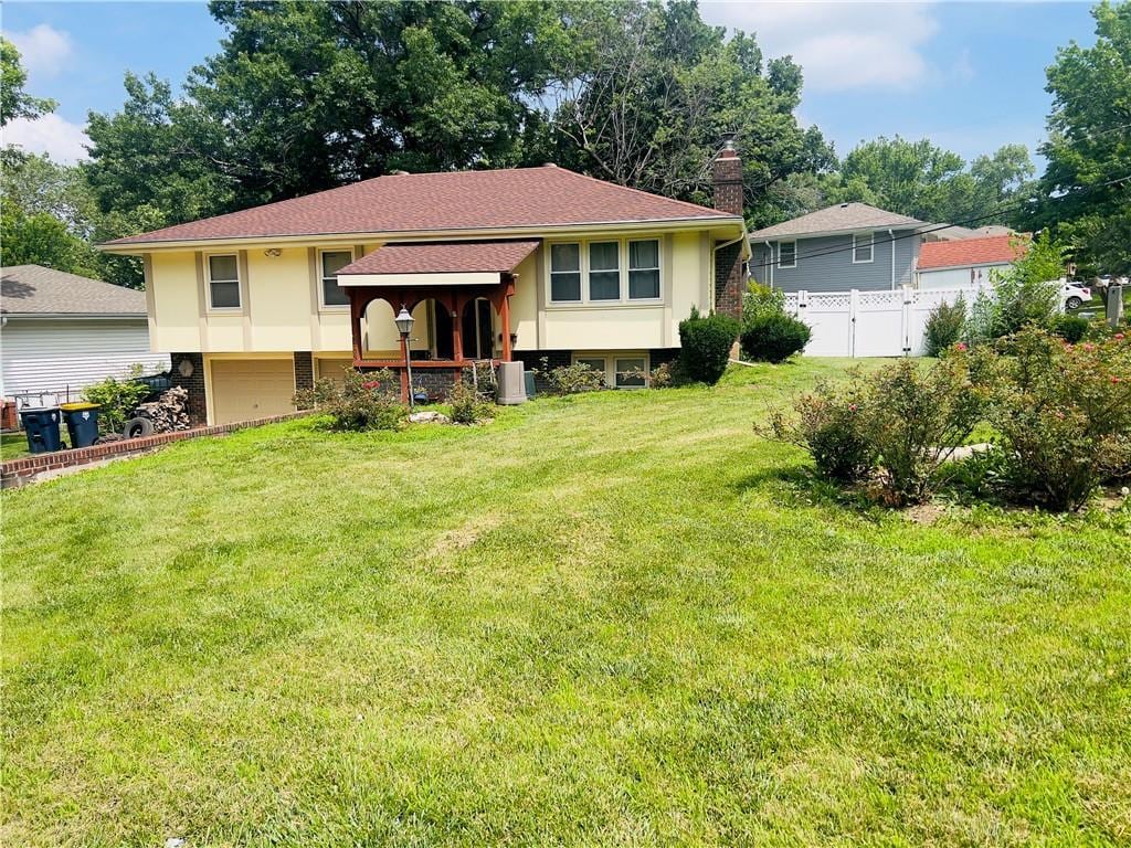 5708 E 100th St, Kansas City, MO 64137 - split foyer home with stucco siding, an attached garage, and a chimney