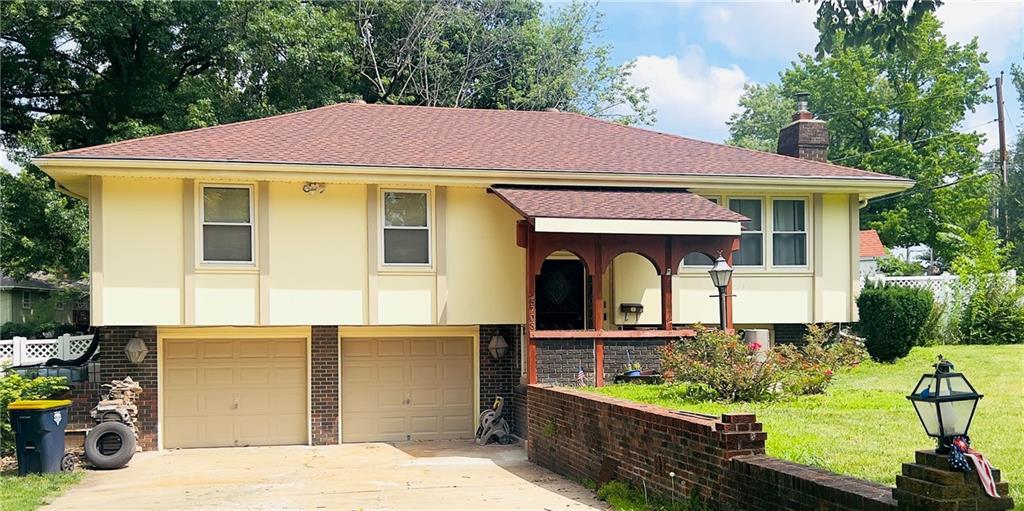 5708 E 100th St, Kansas City, MO 64137 - view of front of house featuring brick siding, stucco siding, an attached garage, a chimney, and a front lawn