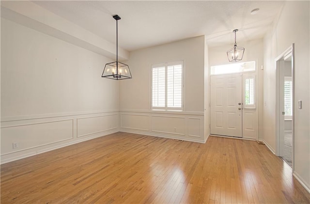 6306 W 128th St, Overland Park, KS 66209 - foyer entrance with a chandelier, light wood-style flooring, wainscoting, and a decorative wall