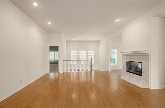 6306 W 128th St, Overland Park, KS 66209 - unfurnished living room with wood finished floors, a tiled fireplace, and recessed lighting