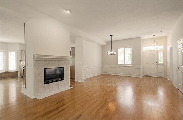 6306 W 128th St, Overland Park, KS 66209 - unfurnished living room with wood finished floors, a tiled fireplace, a wainscoted wall, and a decorative wall