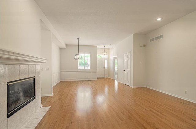 6306 W 128th St, Overland Park, KS 66209 - unfurnished living room with light wood-style flooring, a tile fireplace, recessed lighting, and a chandelier