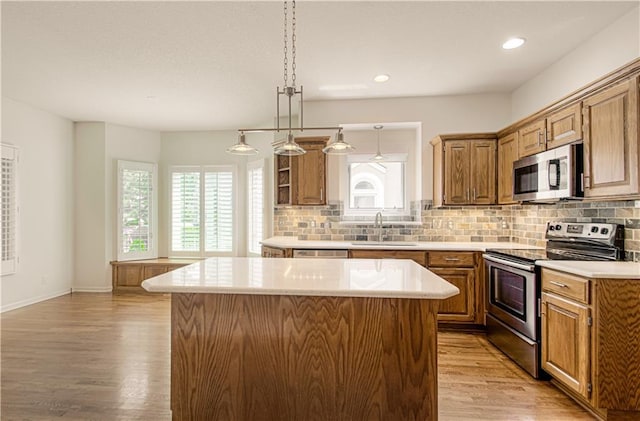 6306 W 128th St, Overland Park, KS 66209 - kitchen featuring stainless steel appliances, a center island, light wood-style flooring, light countertops, and decorative backsplash