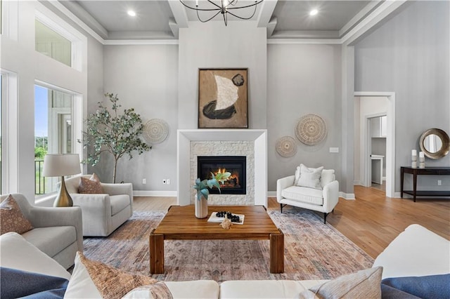 15837 El Monte St, Overland Park, KS 66224 - living area with a towering ceiling, wood finished floors, a stone fireplace, a chandelier, and crown molding