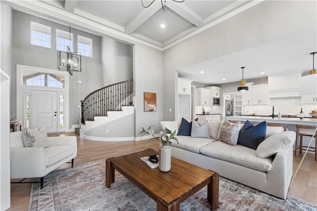15837 El Monte St, Overland Park, KS 66224 - living room with a towering ceiling, a chandelier, stairway, light wood finished floors, and beam ceiling