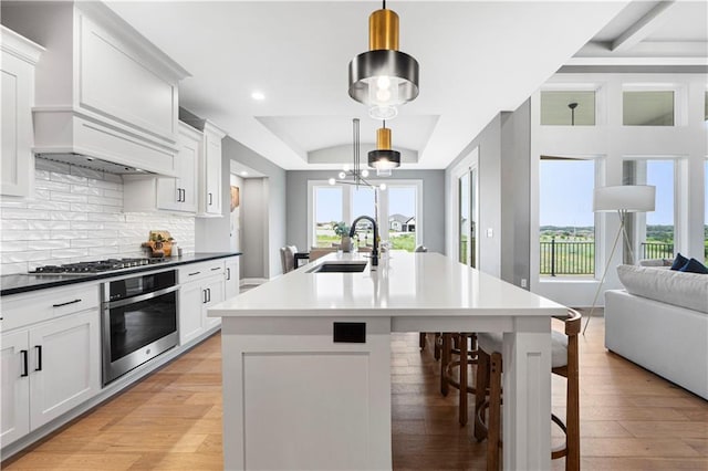 15837 El Monte St, Overland Park, KS 66224 - kitchen with appliances with stainless steel finishes, open floor plan, light wood-type flooring, a kitchen breakfast bar, and an island with sink