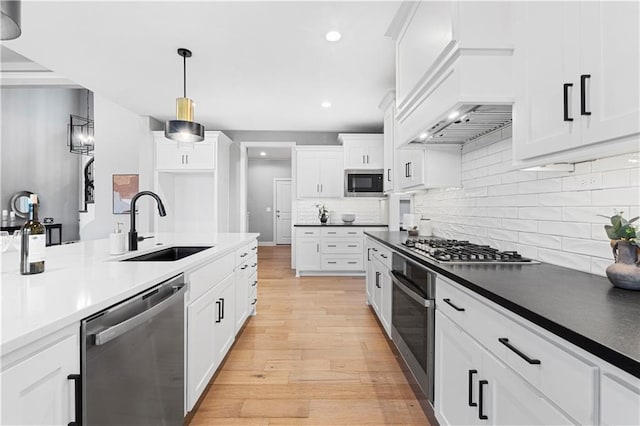 15837 El Monte St, Overland Park, KS 66224 - kitchen featuring stainless steel appliances, light wood finished floors, pendant lighting, backsplash, and white cabinetry