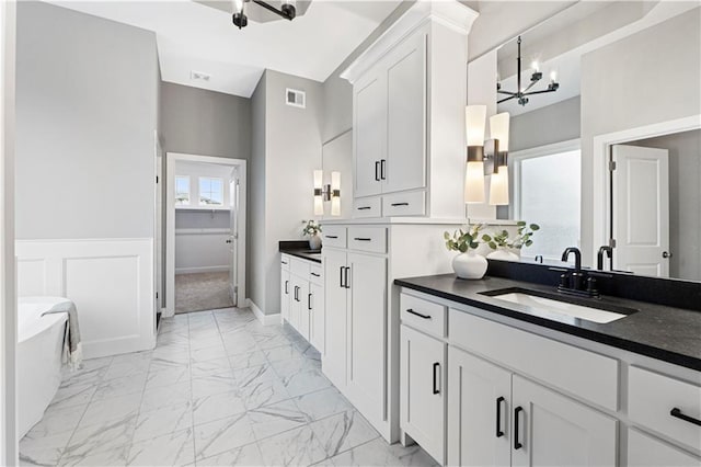 15837 El Monte St, Overland Park, KS 66224 - bathroom with marble finish floors, a soaking tub, vanity, and wainscoting