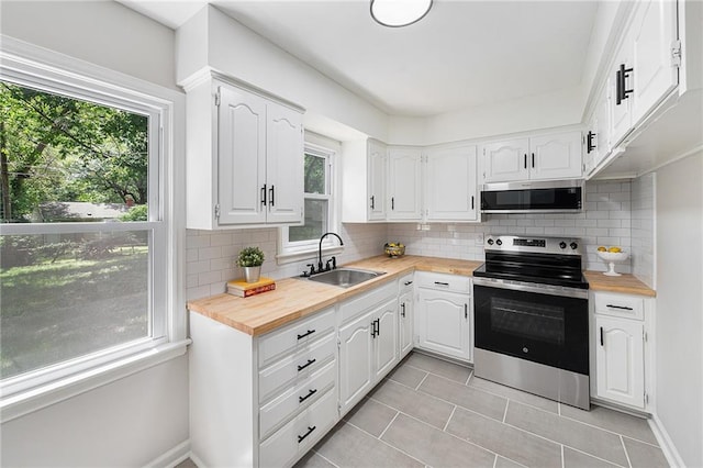 9023 E 74th Ter, Raytown, MO 64133 - kitchen with appliances with stainless steel finishes, light tile patterned floors, wooden counters, and white cabinetry