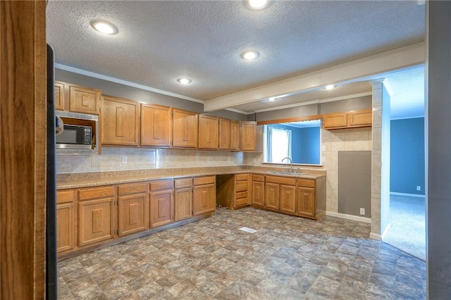 16100 E Elm St, Independence, MO 64050 - kitchen featuring stainless steel microwave, ornamental molding, a textured ceiling, light countertops, and brown cabinets
