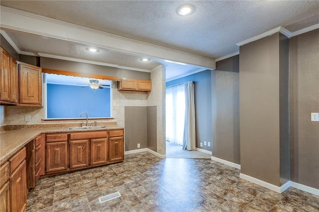 16100 E Elm St, Independence, MO 64050 - kitchen with ornamental molding, a textured ceiling, a ceiling fan, light countertops, and brown cabinetry