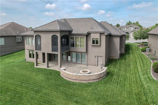 1217 Kingsland Cir, Raymore, MO 64083 - rear view of house with a patio area, a lawn, stucco siding, a balcony, and a tiled roof