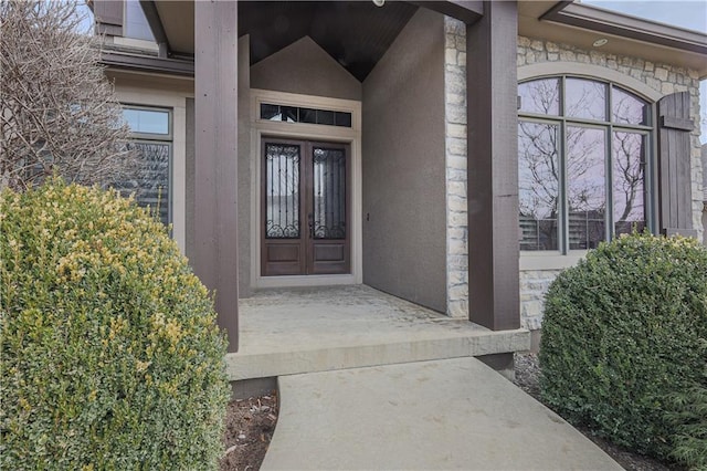 1217 Kingsland Cir, Raymore, MO 64083 - view of exterior entry featuring stone siding, french doors, and stucco siding