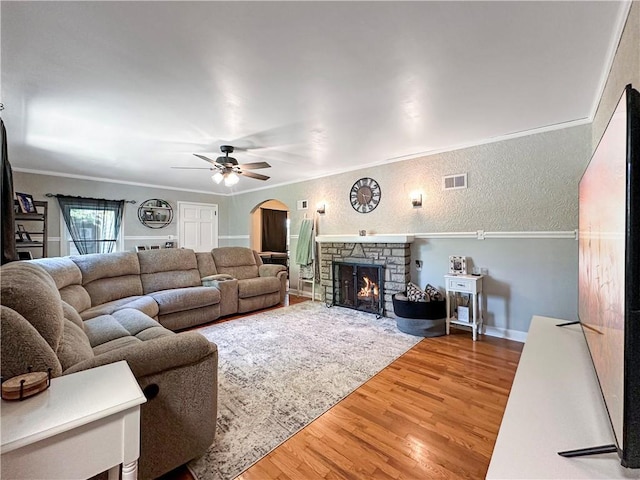 1607 S St, Lexington, MO 64067 - living area featuring arched walkways, wood finished floors, a ceiling fan, a stone fireplace, and a textured wall