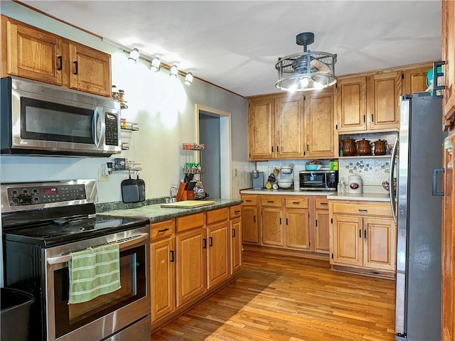 1607 S St, Lexington, MO 64067 - kitchen featuring stainless steel appliances, wood finished floors, decorative backsplash, brown cabinetry, and crown molding