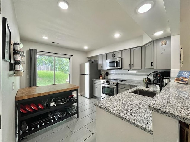 13148 S Brougham Dr, Olathe, KS 66062 - kitchen with appliances with stainless steel finishes, gray cabinets, light stone counters, decorative backsplash, and recessed lighting