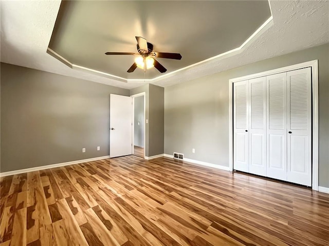 118 Fern St, Lansing, KS 66043 - unfurnished bedroom featuring a tray ceiling, wood finished floors, a ceiling fan, and a closet