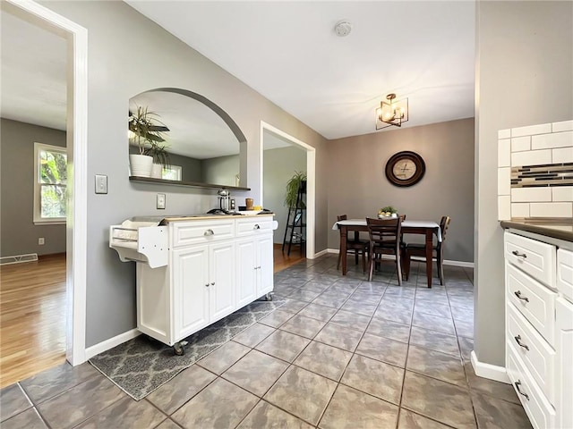118 Fern St, Lansing, KS 66043 - kitchen featuring white cabinets, tile patterned flooring, a chandelier, and arched walkways