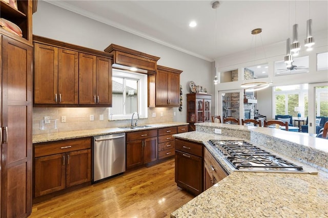 11717 S Barth Rd, Olathe, KS 66061 - kitchen featuring appliances with stainless steel finishes, crown molding, pendant lighting, light wood finished floors, and decorative backsplash