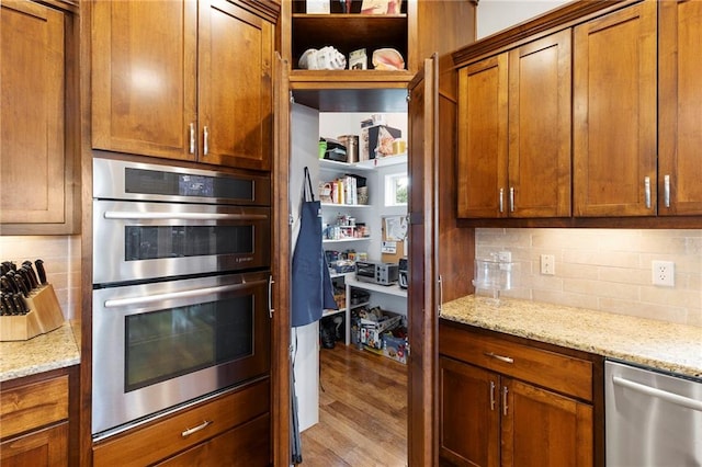 11717 S Barth Rd, Olathe, KS 66061 - kitchen with stainless steel appliances, backsplash, brown cabinetry, wood finished floors, and light stone countertops