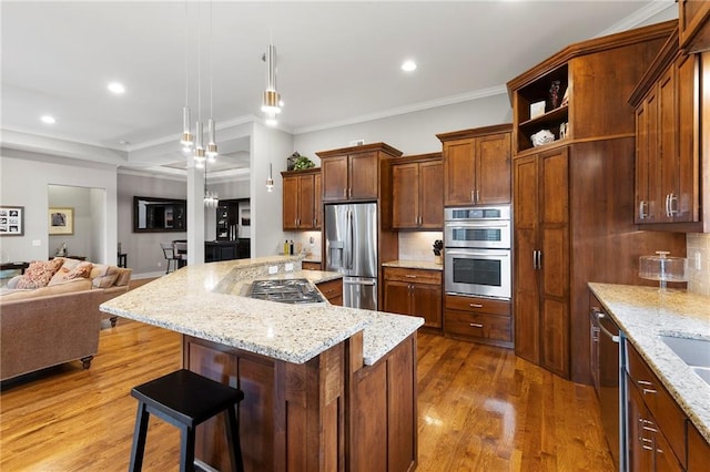 11717 S Barth Rd, Olathe, KS 66061 - kitchen with appliances with stainless steel finishes, open floor plan, wood finished floors, a breakfast bar, and a kitchen island