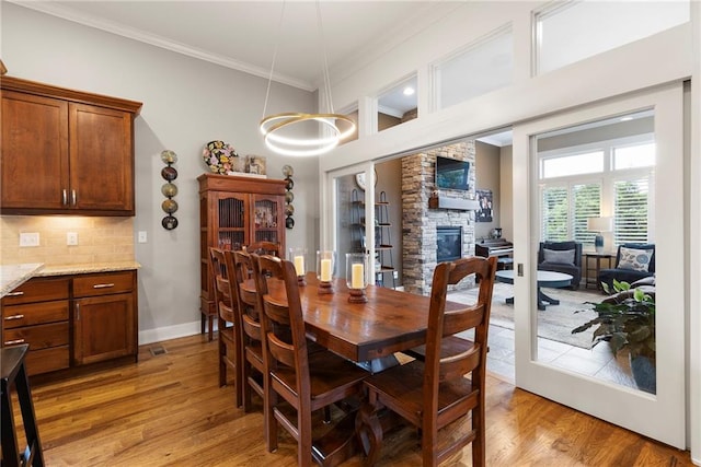 11717 S Barth Rd, Olathe, KS 66061 - dining space with crown molding, light wood-style flooring, and a fireplace