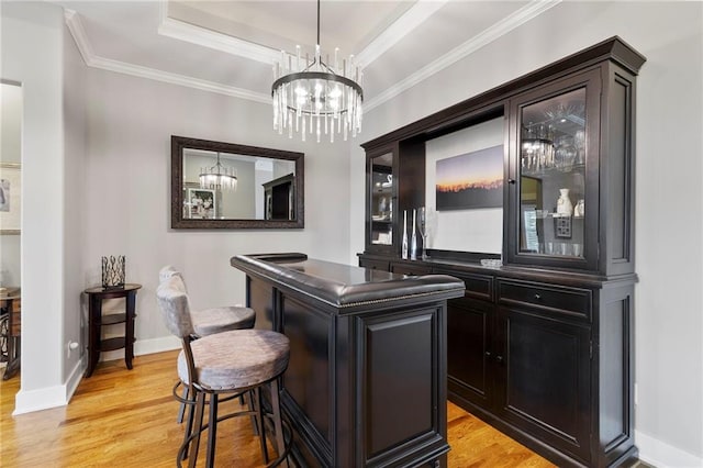 11717 S Barth Rd, Olathe, KS 66061 - bar featuring light wood finished floors, a chandelier, crown molding, a tray ceiling, and hanging light fixtures