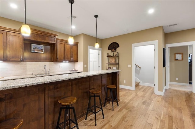 11717 S Barth Rd, Olathe, KS 66061 - kitchen featuring tasteful backsplash, light wood-style floors, a kitchen breakfast bar, pendant lighting, and recessed lighting
