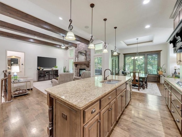 11599 S Carbondale St, Olathe, KS 66061 - kitchen with a fireplace, light wood finished floors, light stone countertops, decorative light fixtures, and beam ceiling