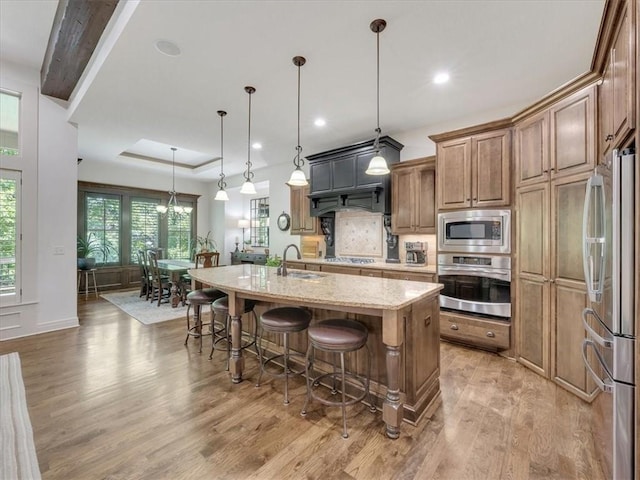 11599 S Carbondale St, Olathe, KS 66061 - kitchen with stainless steel appliances, light wood-style flooring, backsplash, a breakfast bar area, and an island with sink