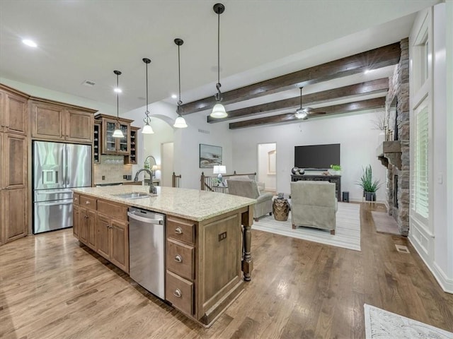 11599 S Carbondale St, Olathe, KS 66061 - kitchen with appliances with stainless steel finishes, a ceiling fan, brown cabinets, a kitchen island with sink, and beam ceiling
