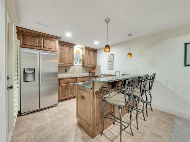 11599 S Carbondale St, Olathe, KS 66061 - kitchen featuring stainless steel fridge with ice dispenser, a breakfast bar area, tasteful backsplash, recessed lighting, and pendant lighting