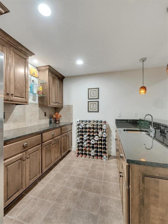 11599 S Carbondale St, Olathe, KS 66061 - kitchen with decorative backsplash, dark stone counters, decorative light fixtures, recessed lighting, and light tile patterned floors