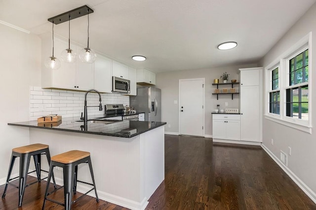4309 S Huntington Way, Independence, MO 64055 - kitchen with stainless steel appliances, a peninsula, tasteful backsplash, white cabinetry, and dark wood-style flooring